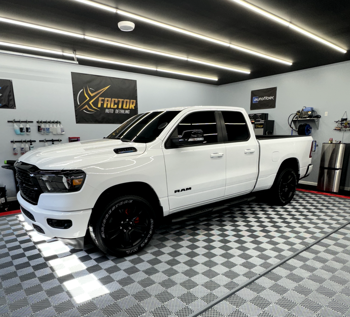 a white truck is parked in a garage with a checkered floor .
