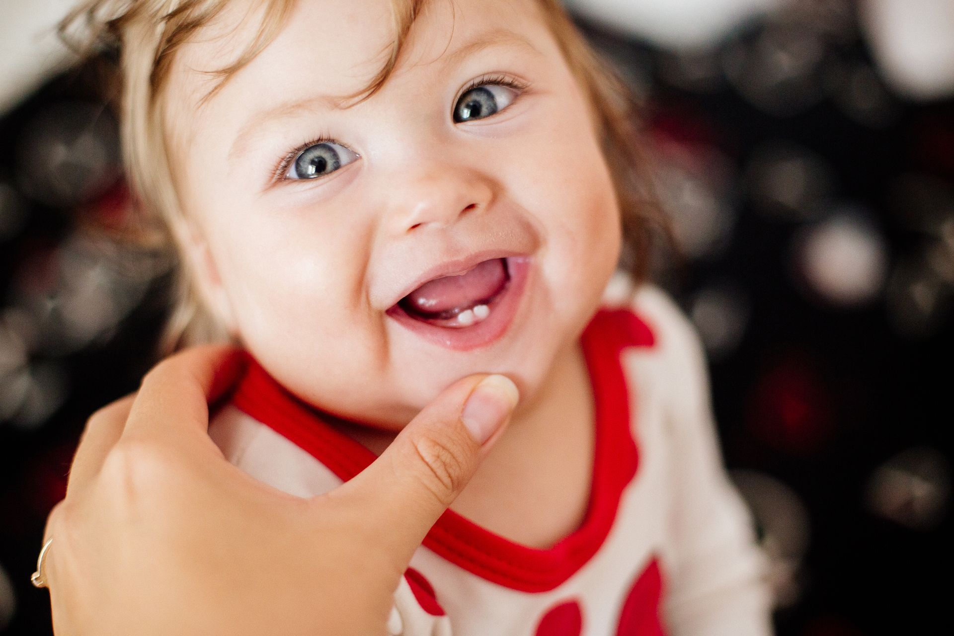 A baby with a missing tooth is smiling while being held by a person.