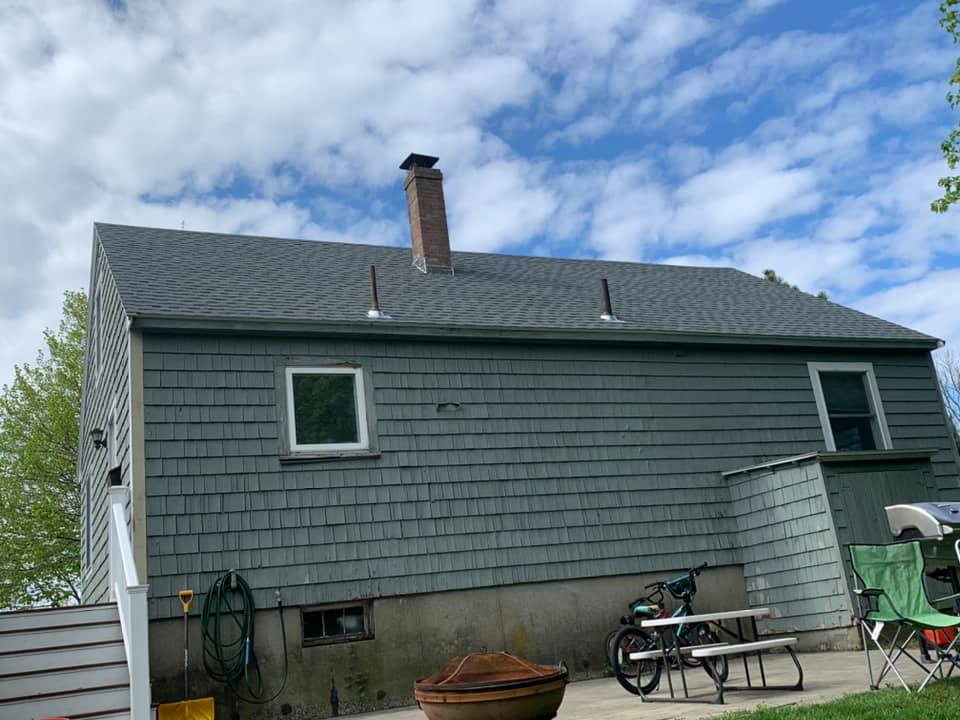 A house with a picnic table and chairs in front of it.