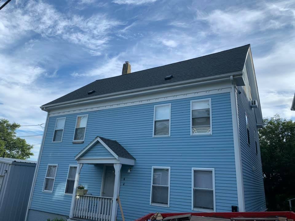 A blue house with a black roof and white trim.