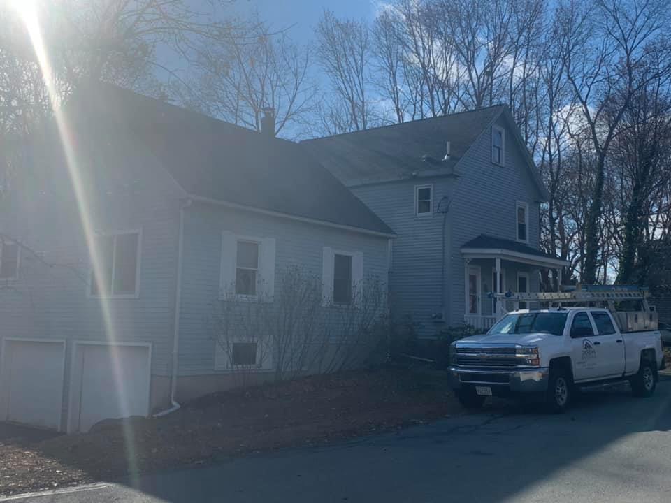 A white truck is parked in front of a white house.