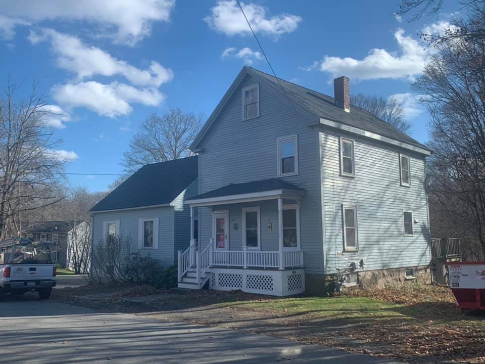 A white house with a porch and a truck parked in front of it.