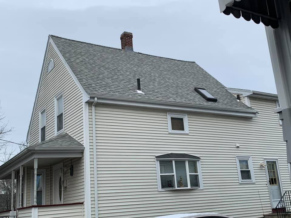 A white house with a gray roof and a chimney.