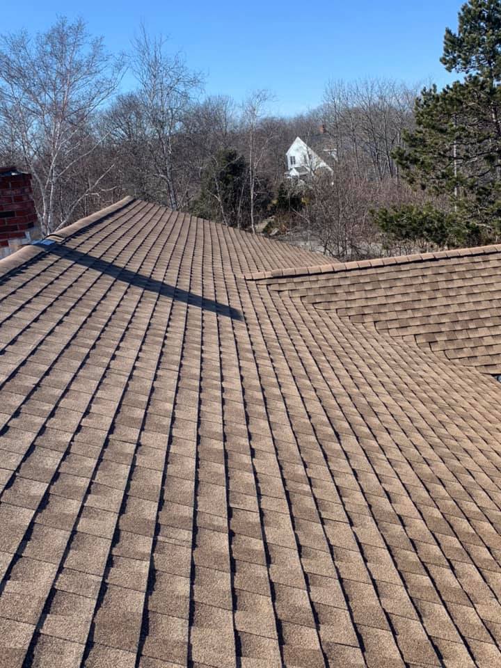 A roof with a lot of tiles on it and a house in the background.
