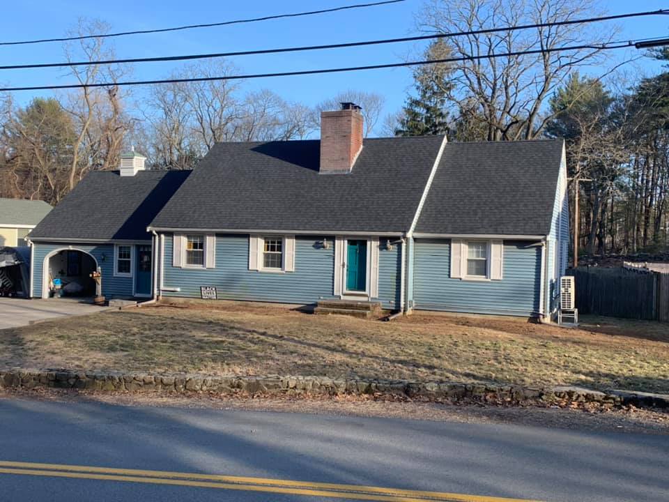 A blue house with a black roof and a garage