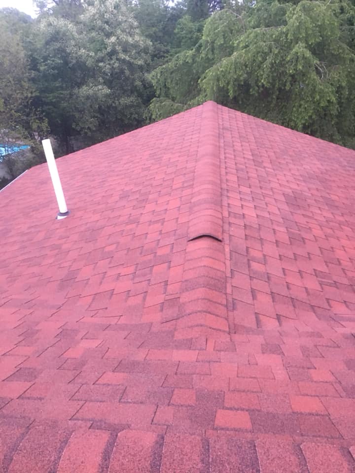 A close up of a red roof with trees in the background.