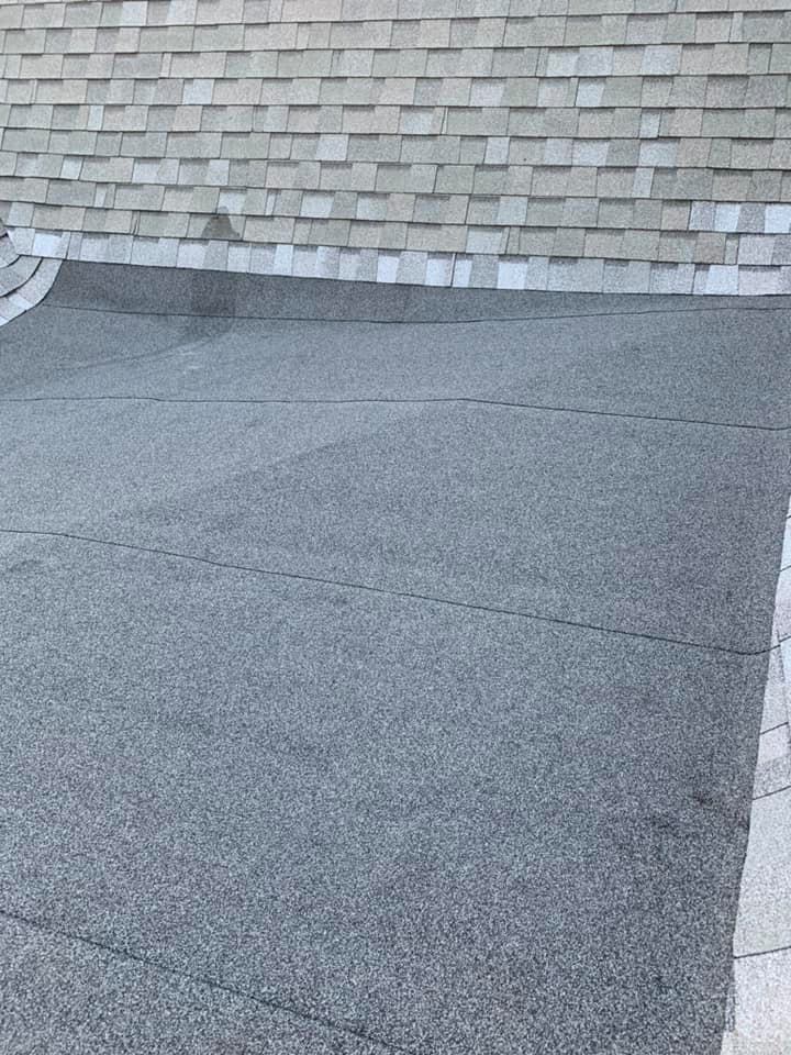 A black roof with a brick wall in the background.