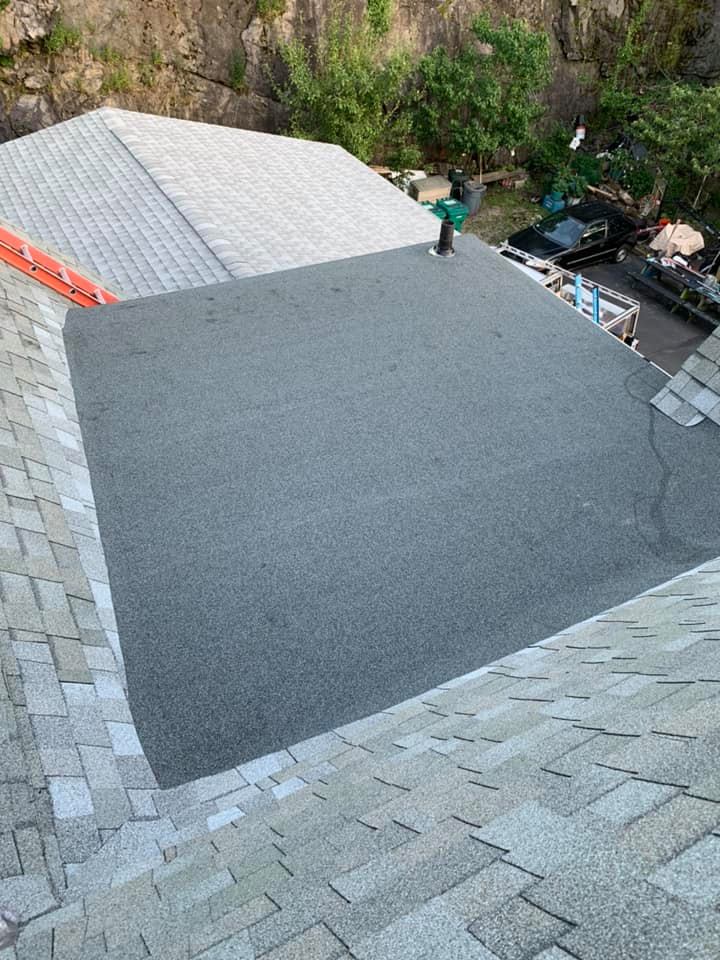 A person is standing on top of a roof with a ladder.