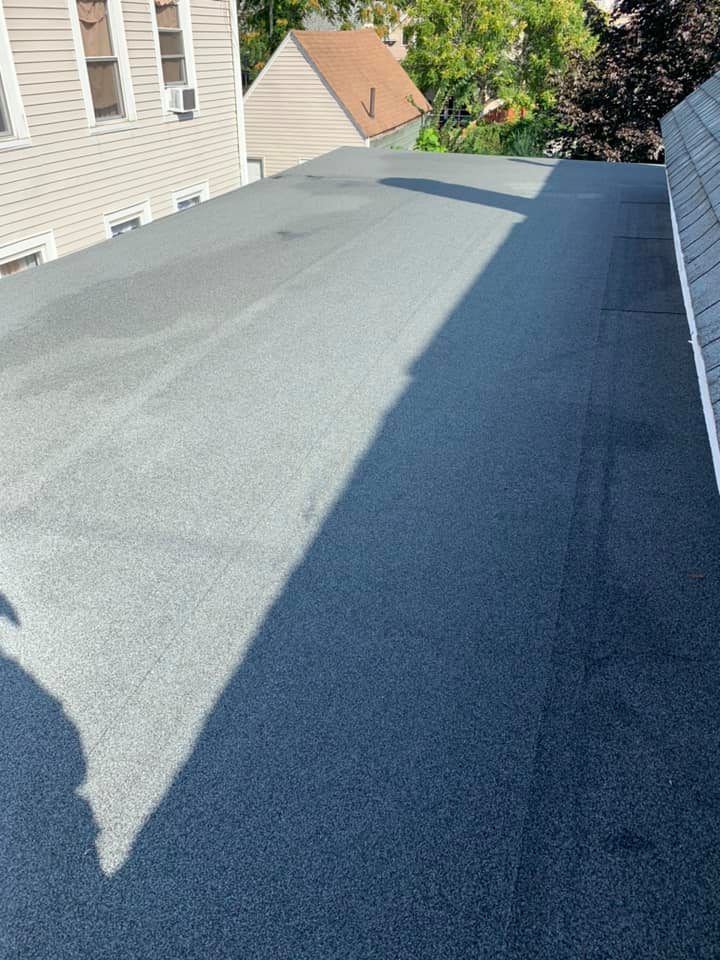 A black roof with a shadow of a building on it.