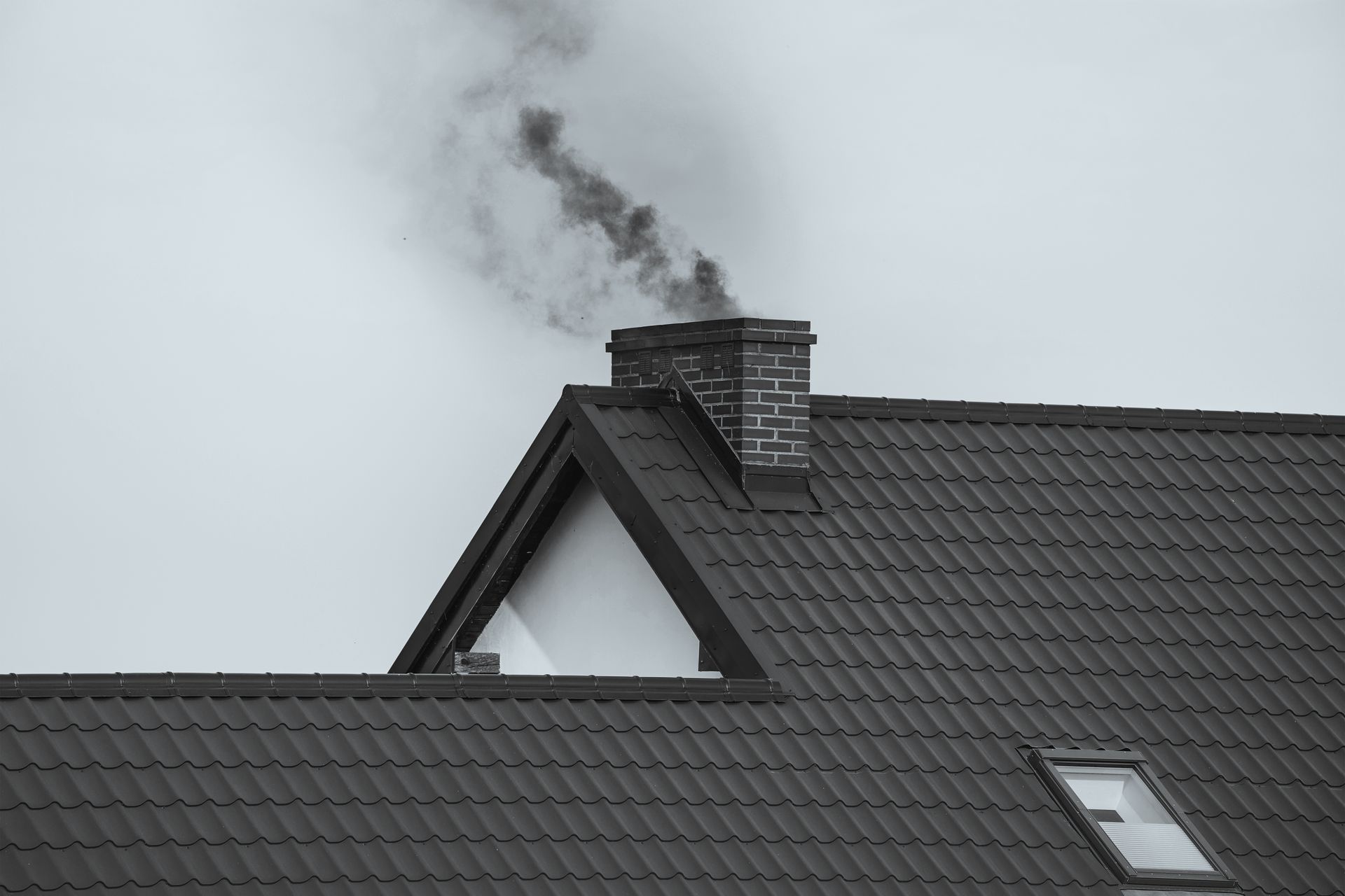 Smoke is coming out of a chimney on the roof of a house.