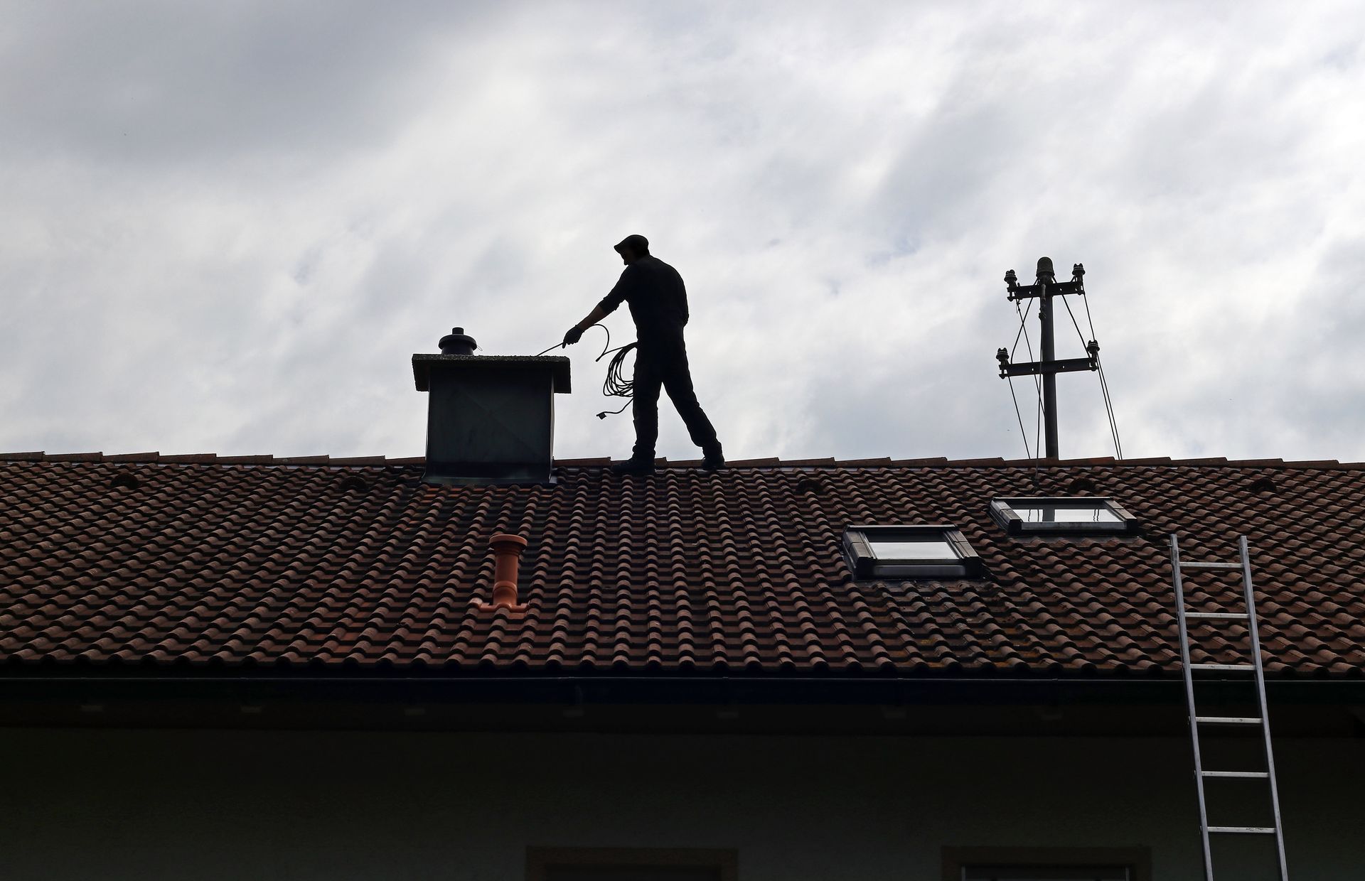 A man standing on top of a roof with a ladder