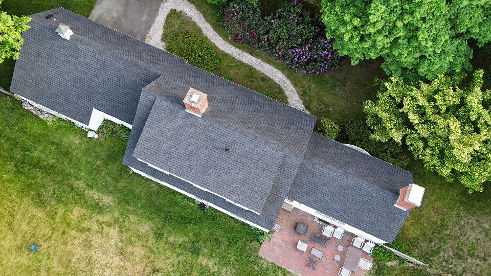 An aerial view of a house with a lot of trees in the background.