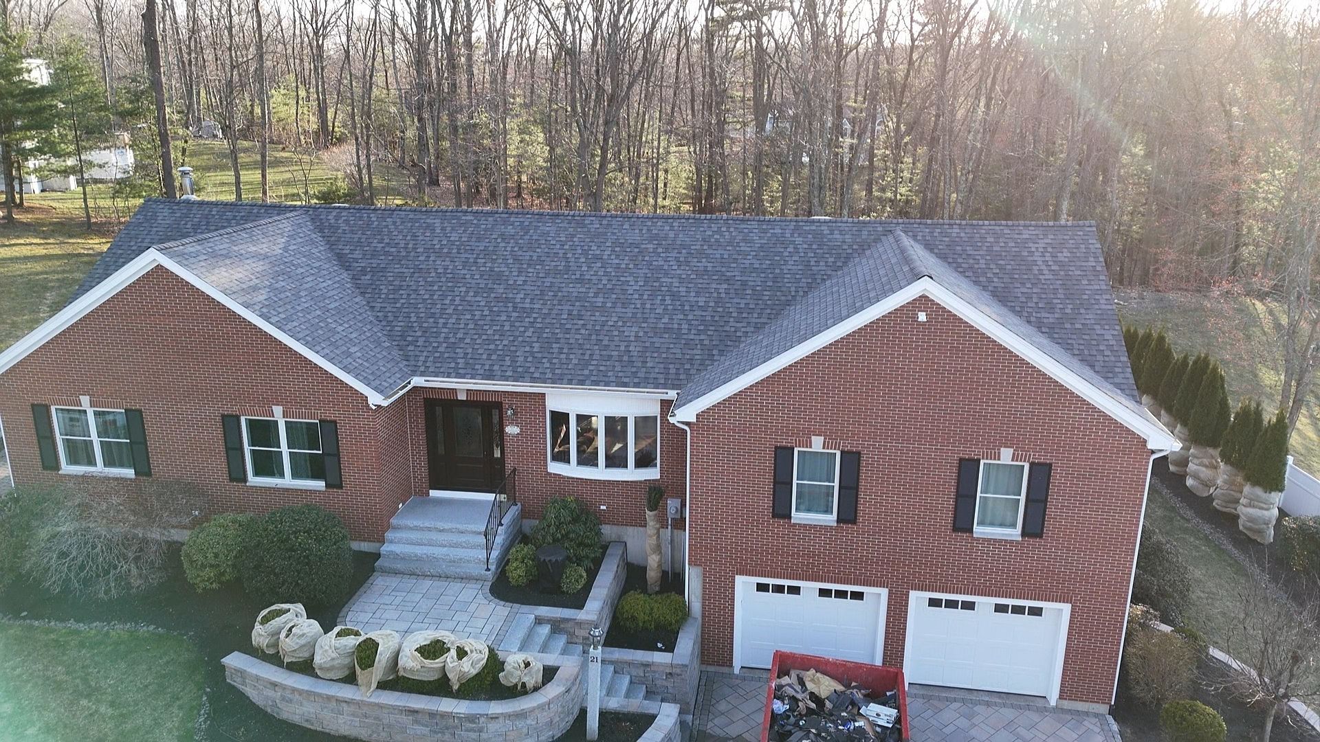 An aerial view of a brick house with a gray roof