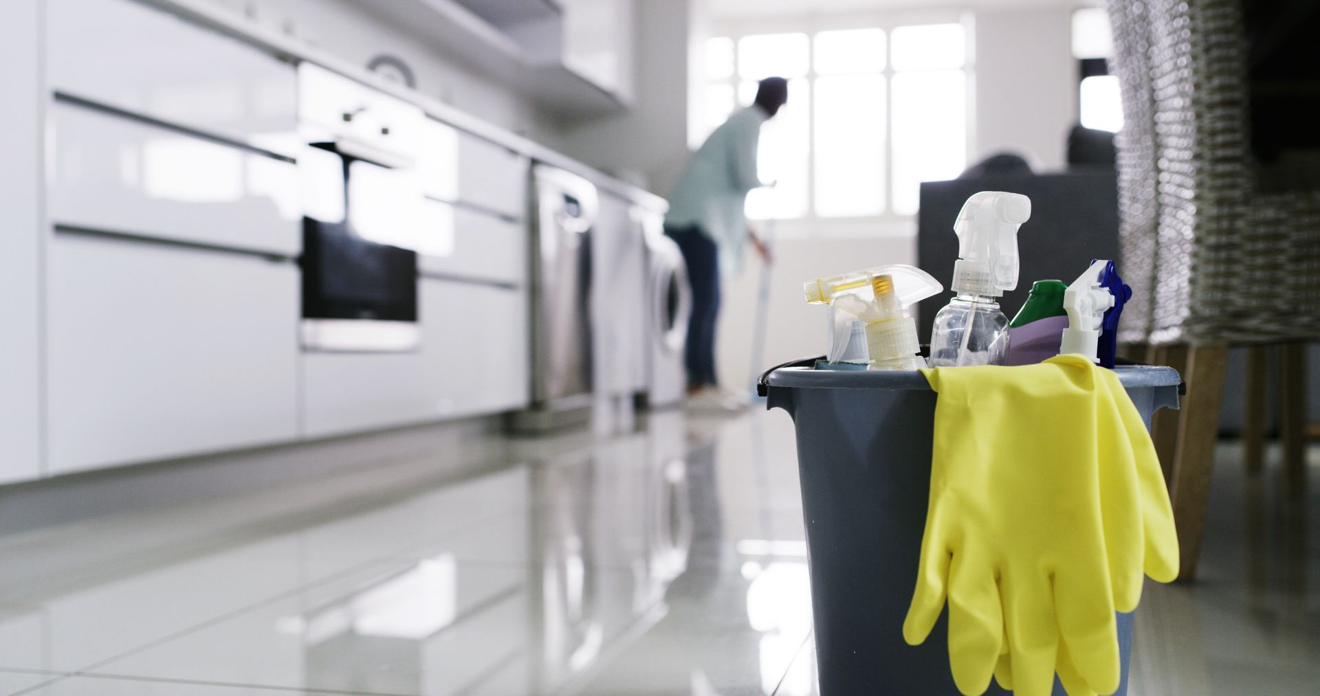 Person in a yellow raincoat cleaning a rug with a floor buffer, creating suds.