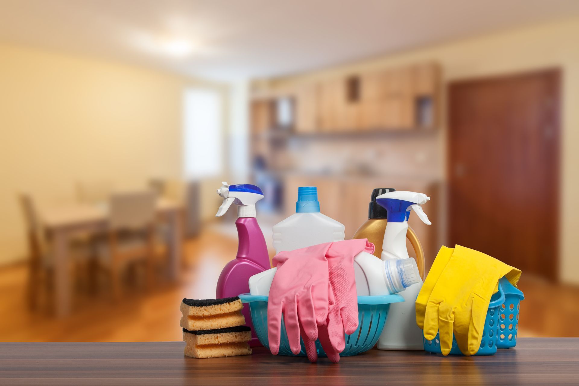 Person in blue uniform holding a pool cleaning net, mop, and a bucket of supplies, on a blue gradient background. Cleaning supplies, including spray bottles, sponges, and rubber gloves in a blue basket, on a table in a home interior.