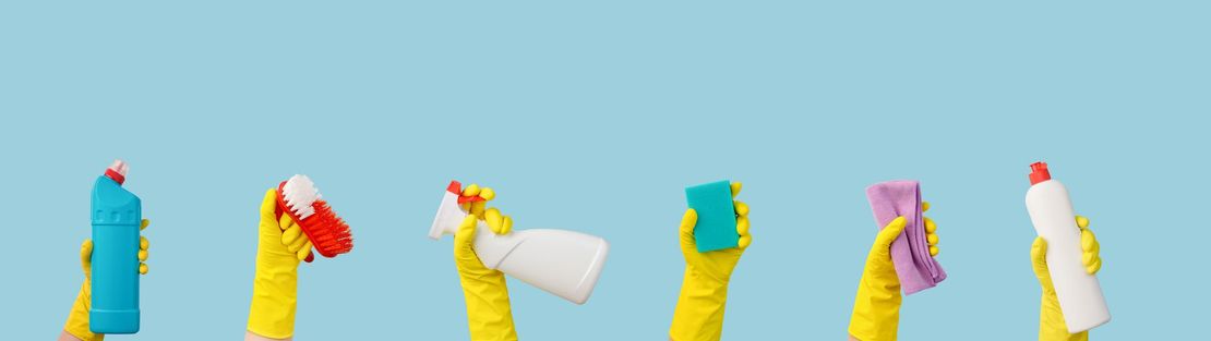 Hands in yellow gloves holding cleaning supplies against a blue background.