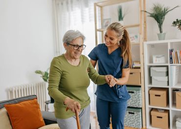 A nurse is helping an elderly woman walk with a cane.