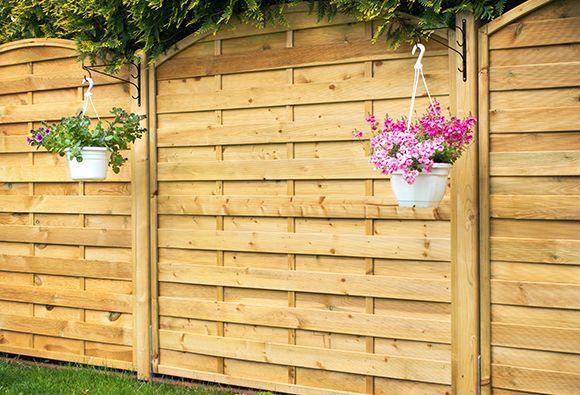 a wooden fence with hanging baskets of flowers on it .