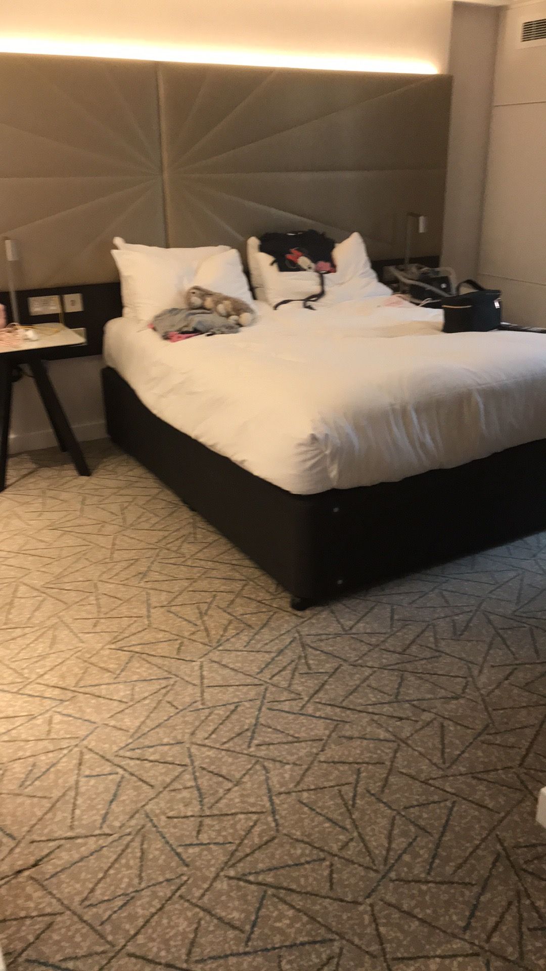 Queen=-sized bed with white duvet and pillows sit in the middle on the bedroom. To either side is a table with a lamp on.