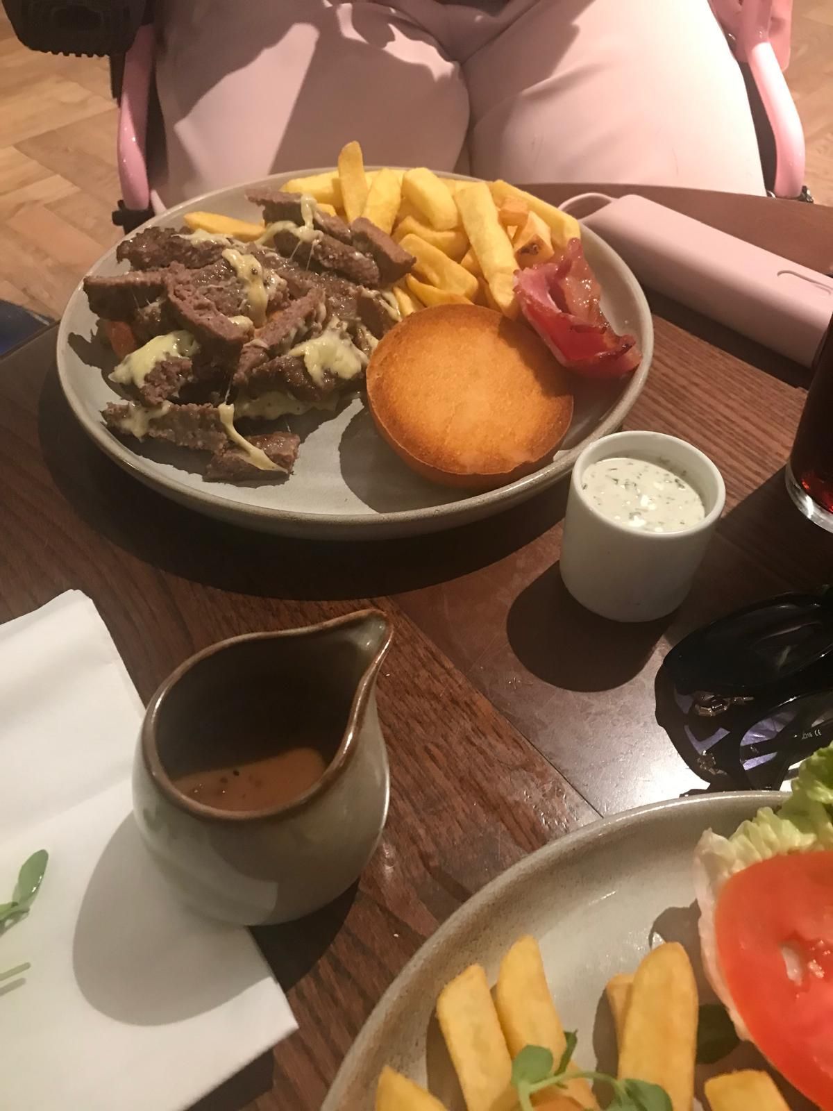 A Burger Bun with a burger and fries sit on a plate. 