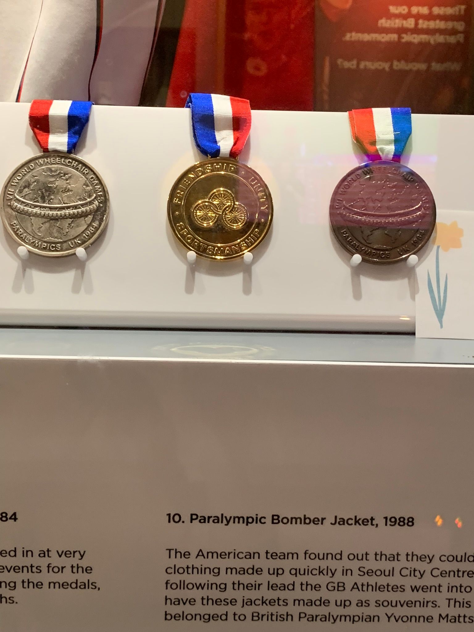 a bronze, silver, and gold medal attached to red, white, and blue ribbon. On a white background.