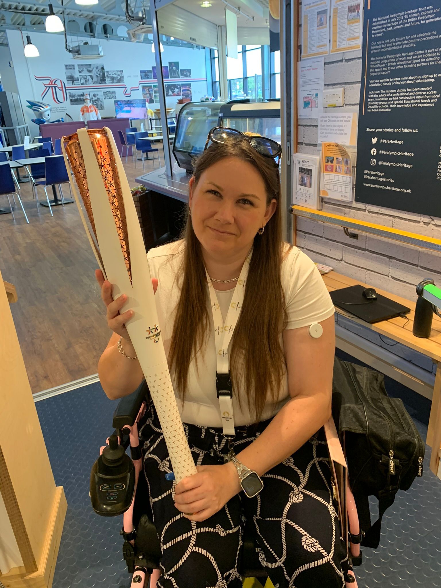 Victoria-Jayne with 2018 Pyeongchang winter Paralympic flame, wearing a white t-shirt, blue and white trousers, and sitting in her wheelchair.