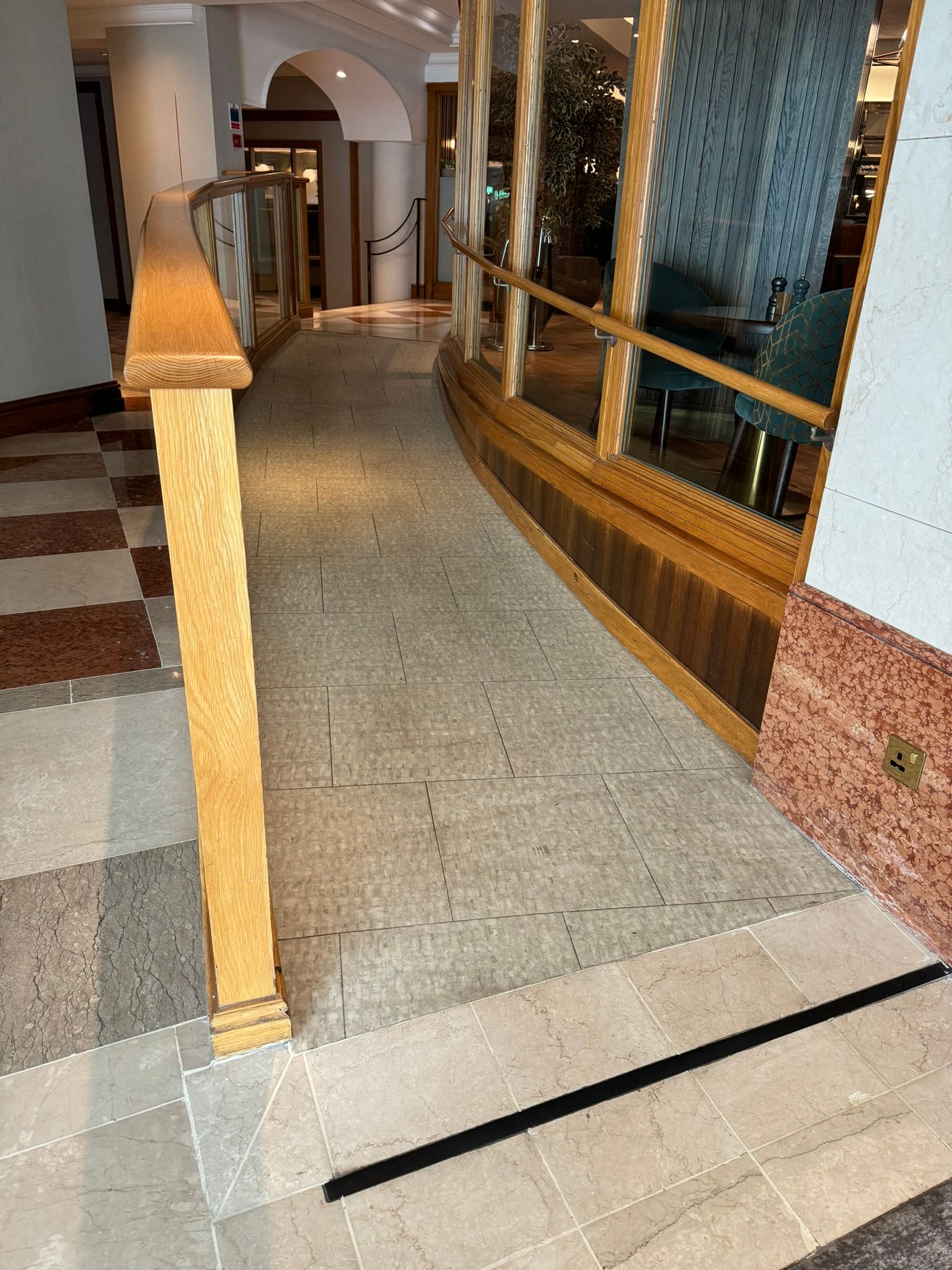 Marble style flooring. Pine handrail on left, glass window on right. 