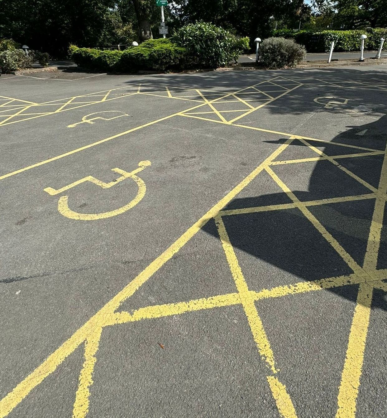 Disabled car parking space, with a disabled sign and yellow crosses to signal no parking. 