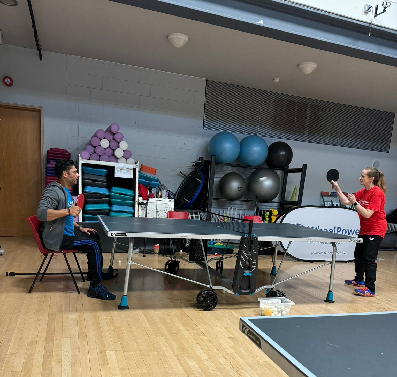 Table Tennis match between participant who is a wheelchair user and non-disabled participant. 