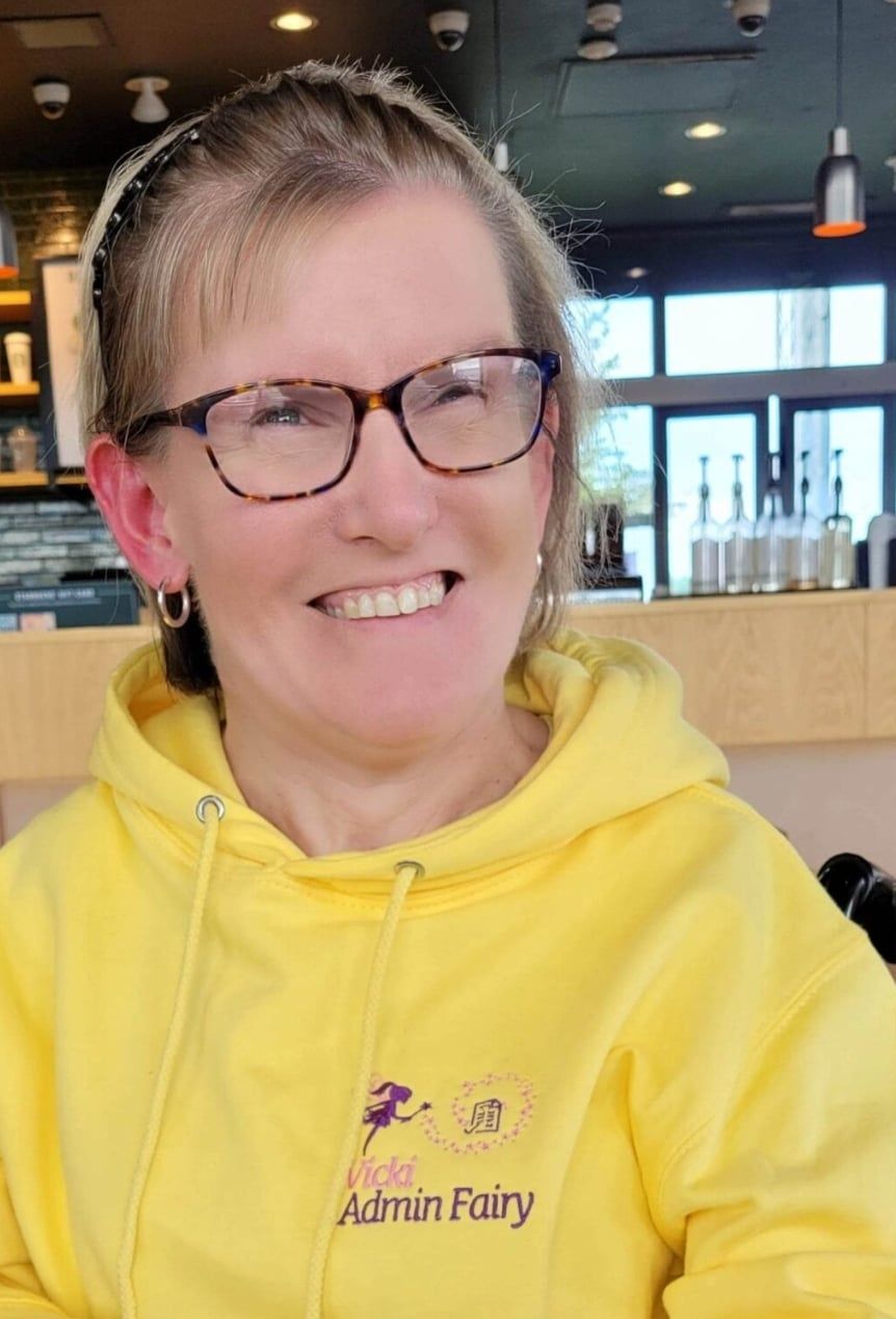 Vicki Wilson, wearing a yellow hoodie branding the Vicki-Admin Fairy Logo in pink on the right-hand side. 