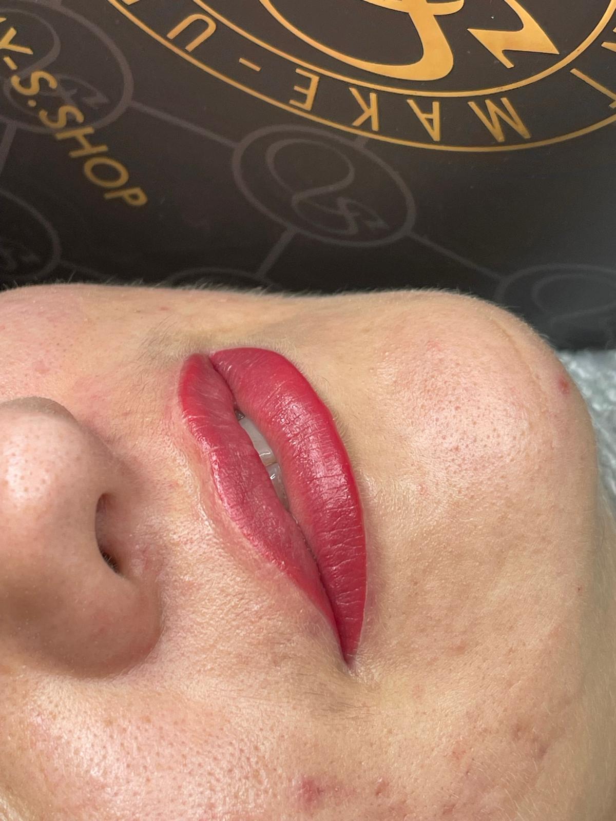 Lips with red cosmetic tattoo on a person's face.