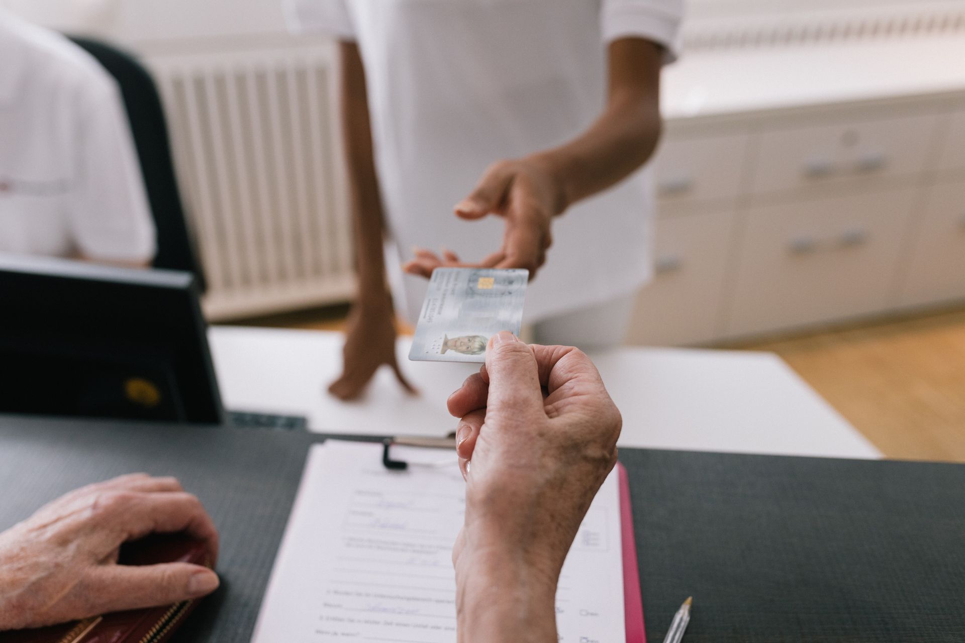 Woman handing receptionist medical insurance card at MRI clinic reception