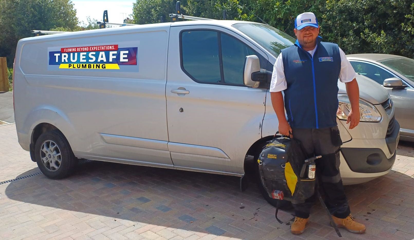 A man is standing in front of a truesafe van.