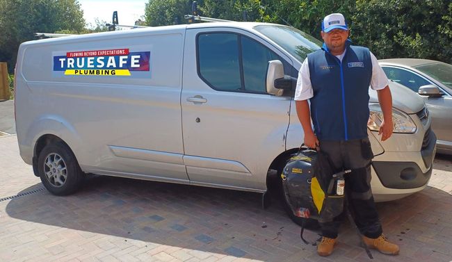 A man is standing in front of a truesafe van.
