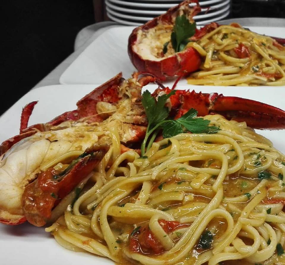 Due piatti di tagliatelle e aragoste su un tavolo