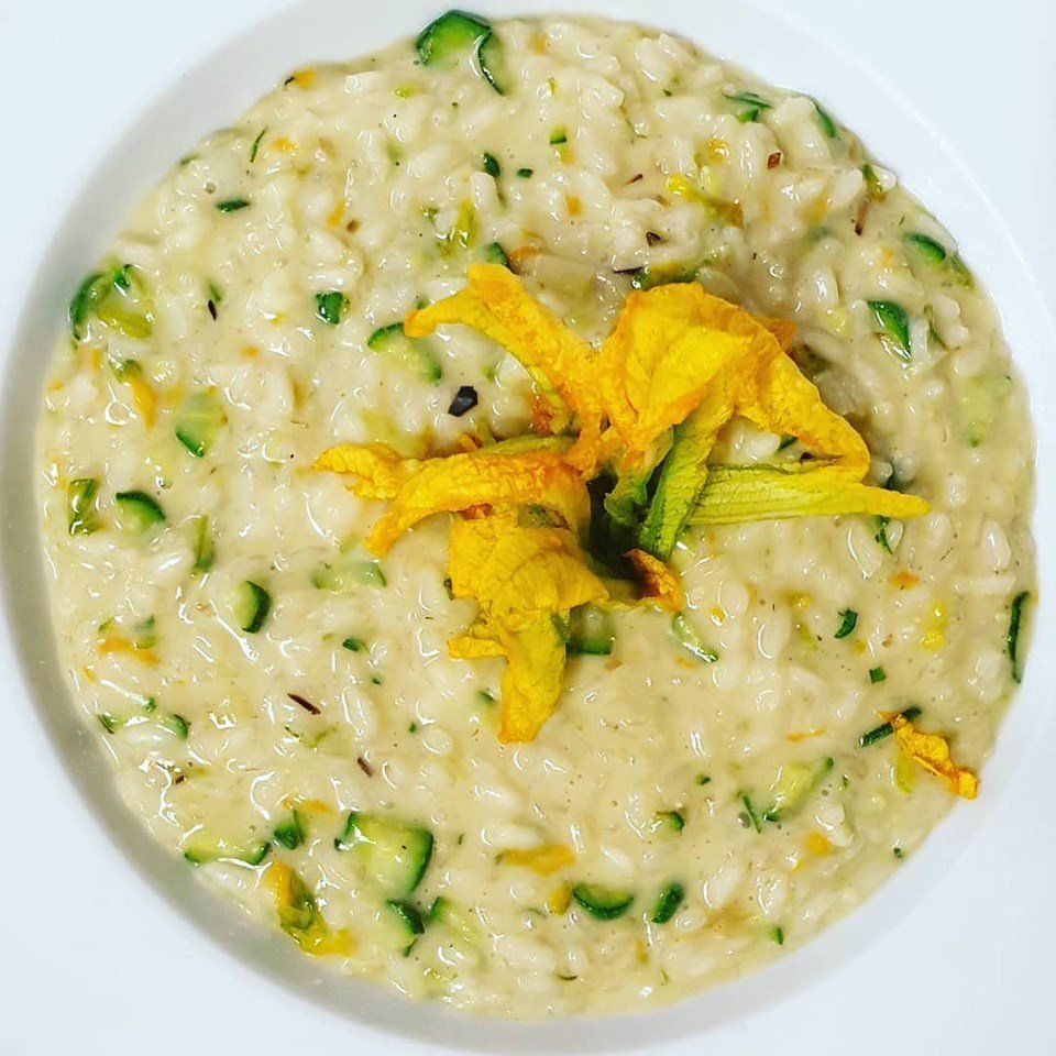 Una ciotola di risotto con un fiore giallo sopra.