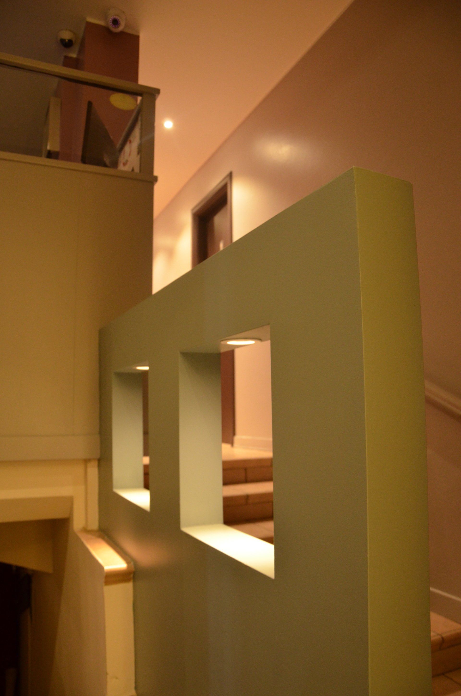 Una stanza con una scala e una parete con degli scaffali