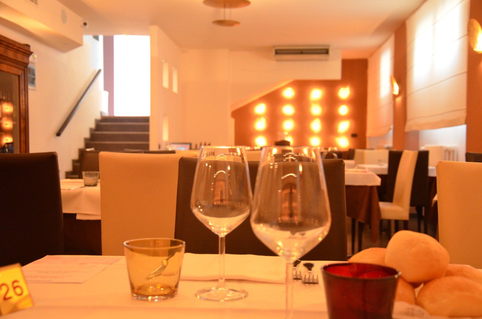 Due bicchieri di vino sono su un tavolo in un ristorante con un cartello giallo che dice 26