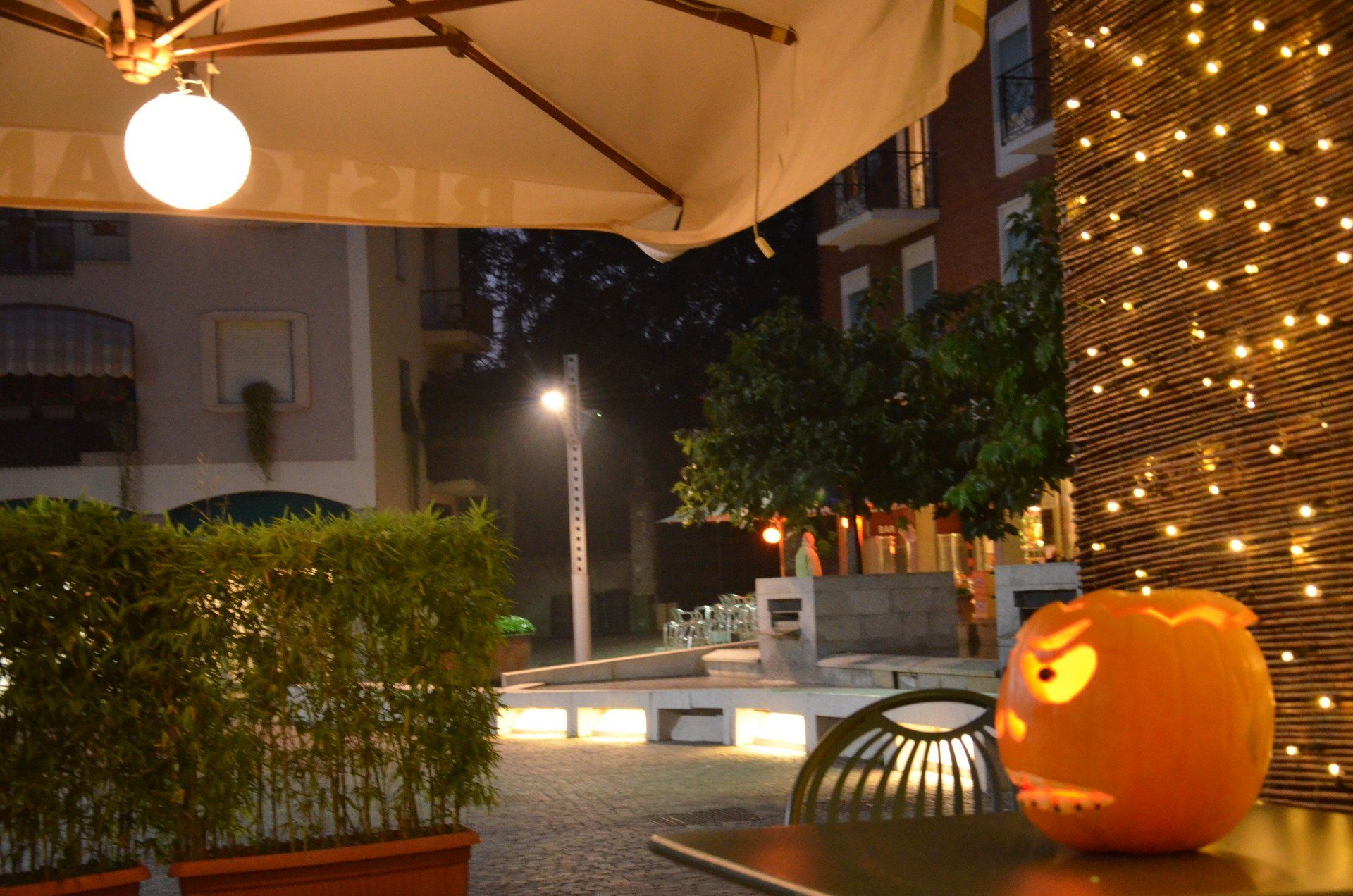 Una zucca con una faccia scolpita è appoggiata su un tavolo sotto un ombrellone