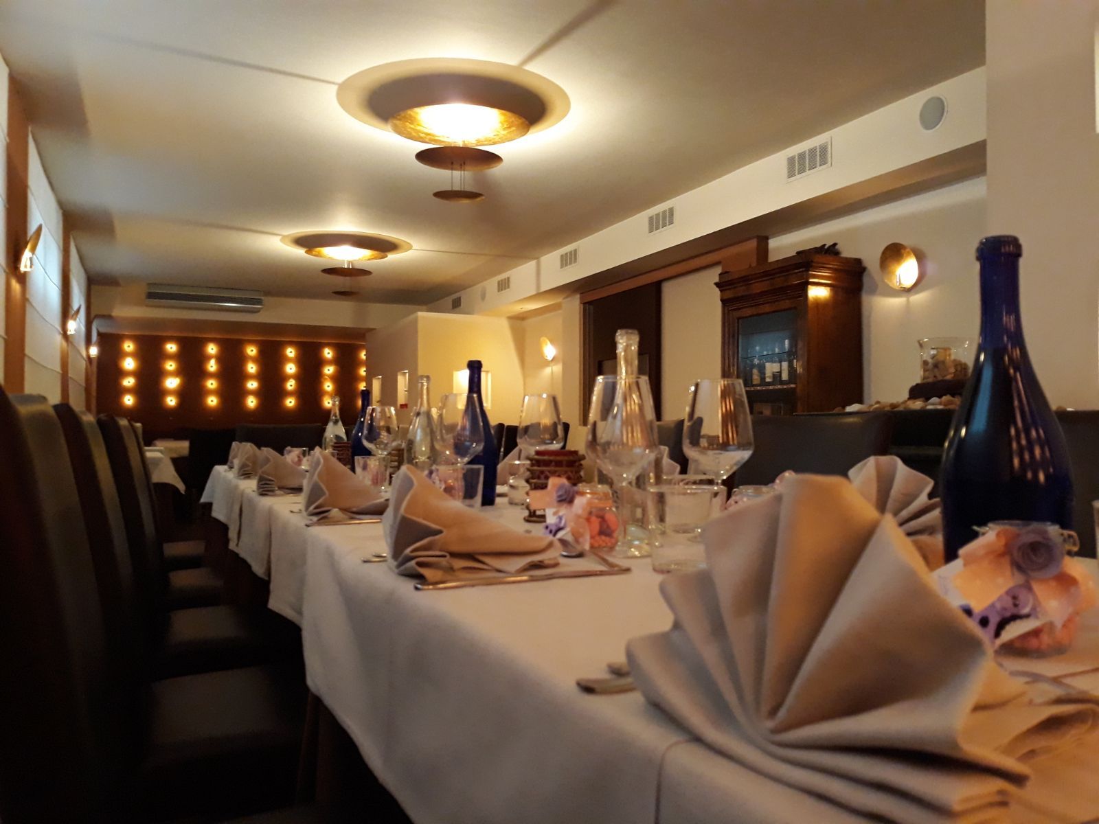 Un lungo tavolo in un ristorante con bottiglie di vino sopra