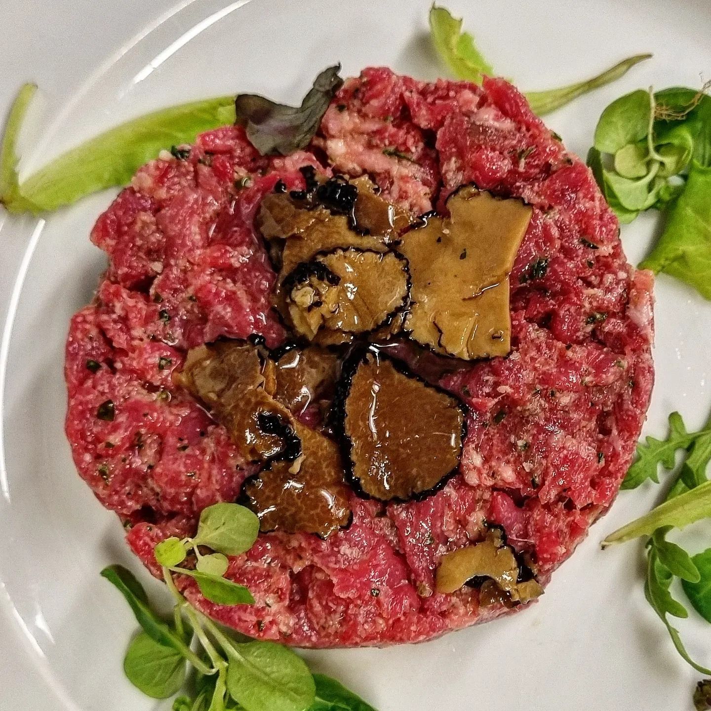 Un piatto di cibo con carne e funghi sopra