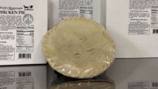 A pie crust is sitting on a table next to a box of pie crusts.