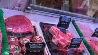 A variety of meats are displayed in a butcher shop.