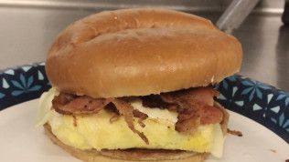 A close up of an egg and bacon sandwich on a plate.