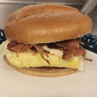 A close up of an egg and bacon sandwich on a plate.