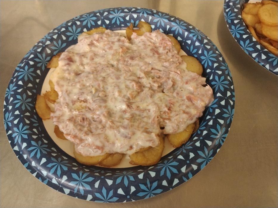 A paper plate with a sauce on top of potatoes