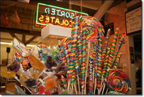 A bunch of colorful lollipops in front of a neon sign