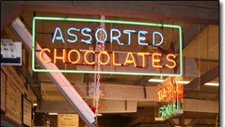 A neon sign that says assorted chocolates in a store window
