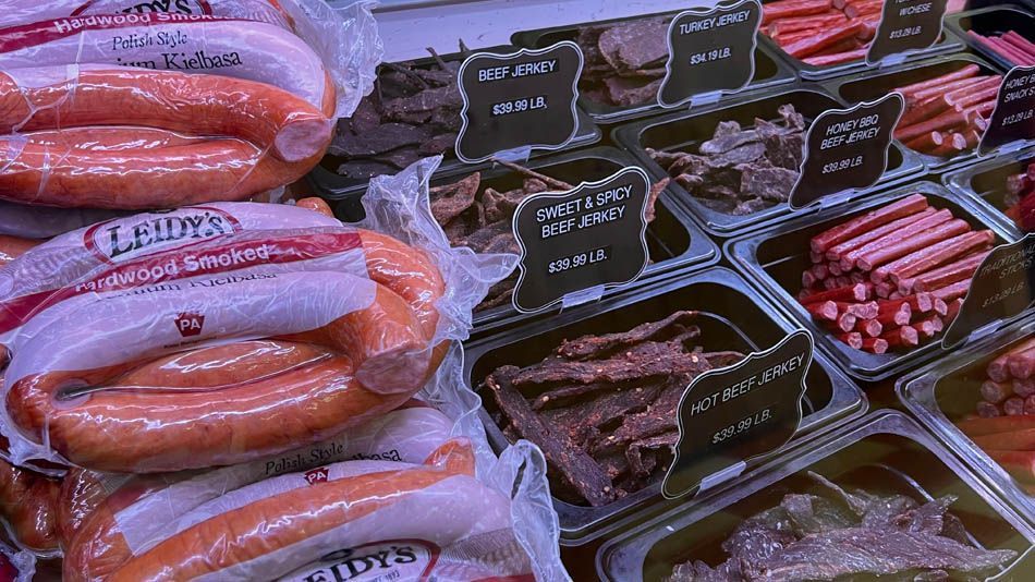 A variety of sausages are displayed on a shelf in a store.