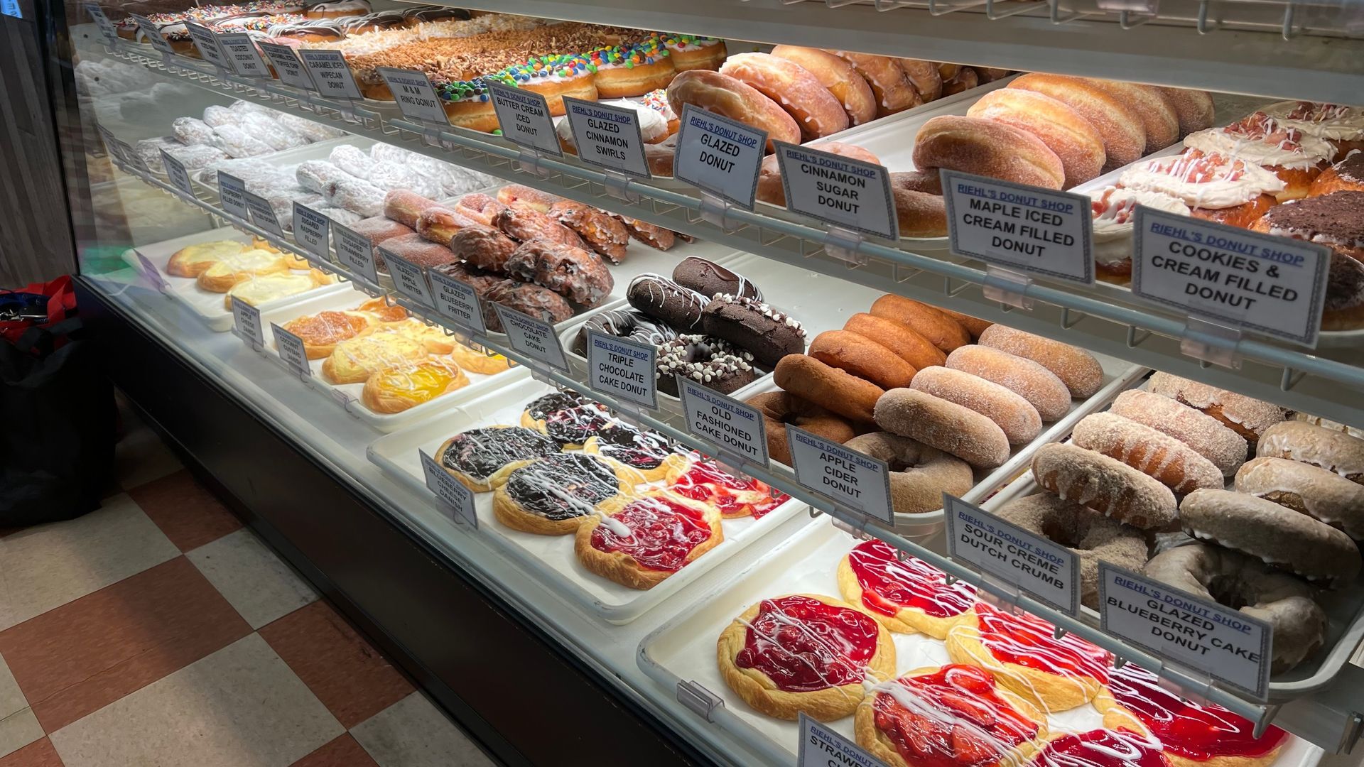 A display case filled with a variety of donuts and pastries.